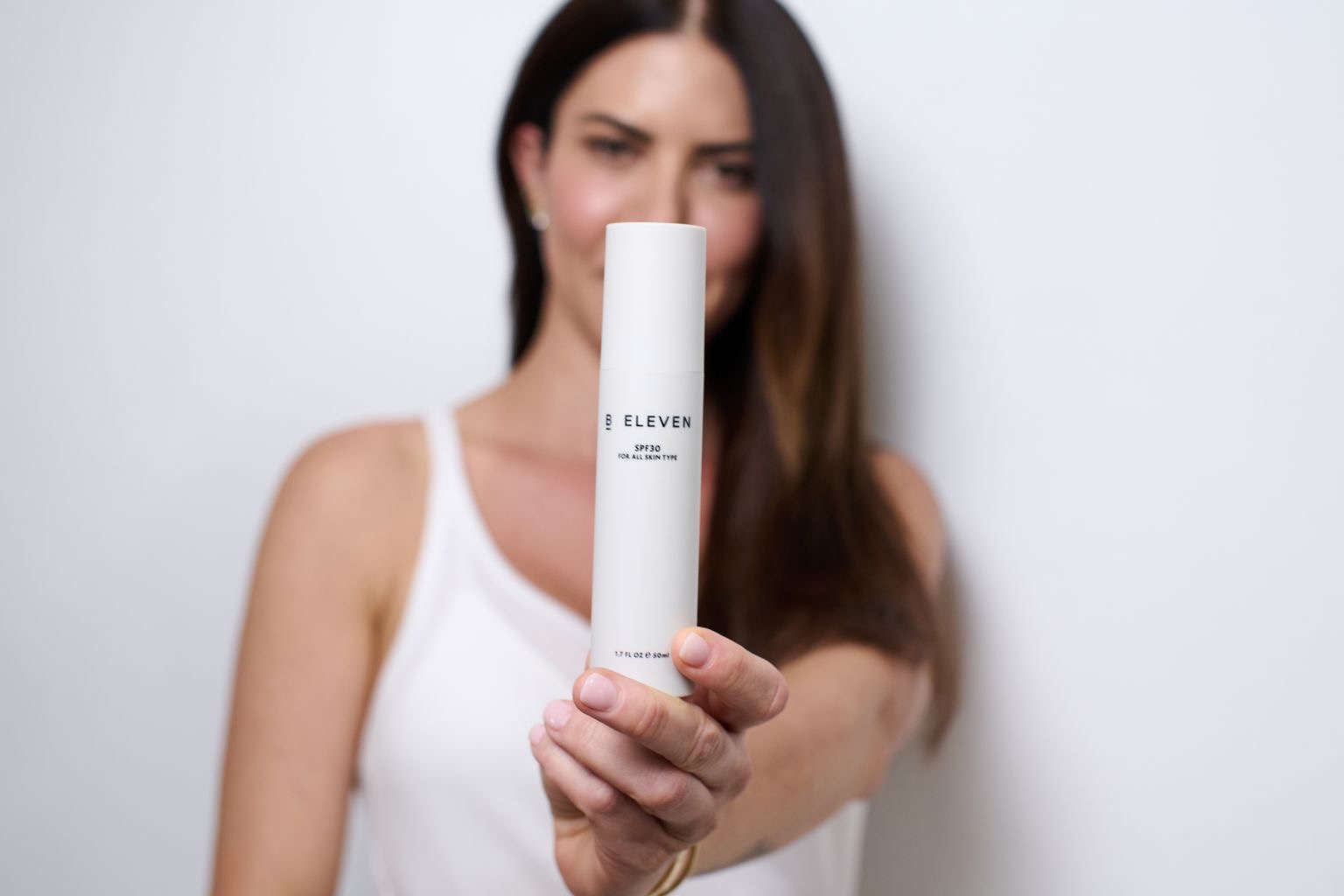 אישה מציגה את קרם ההגנה SPF50 של B ELEVEN